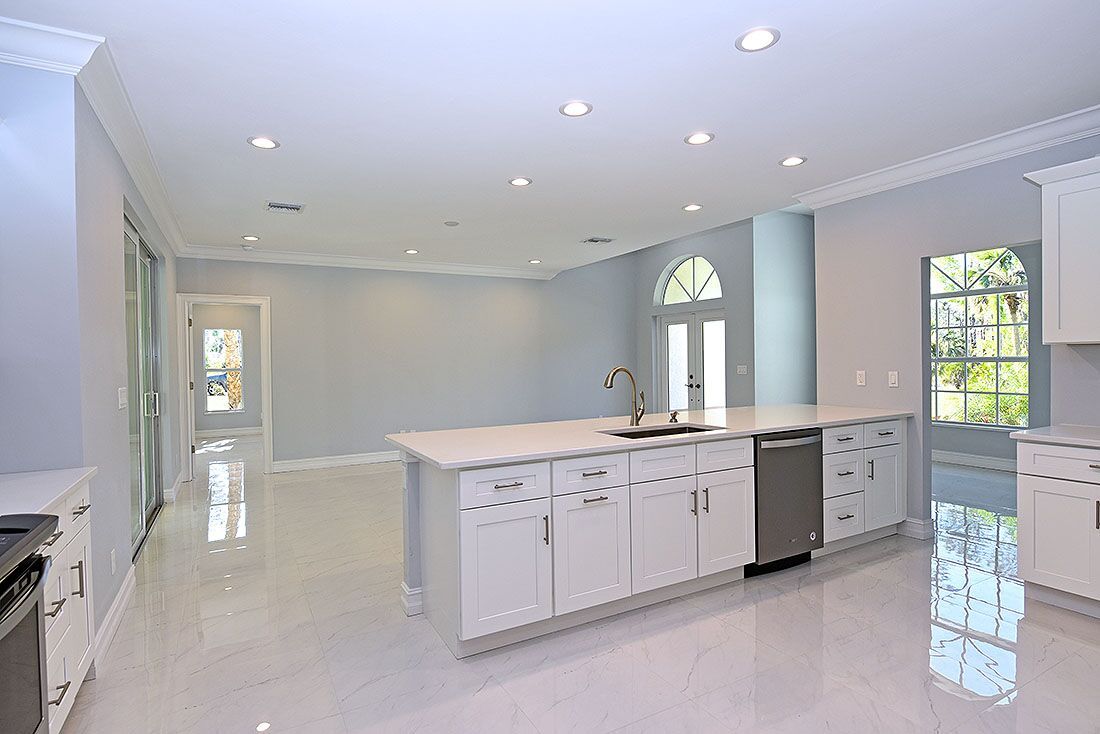 An empty kitchen with white cabinets and a large island.