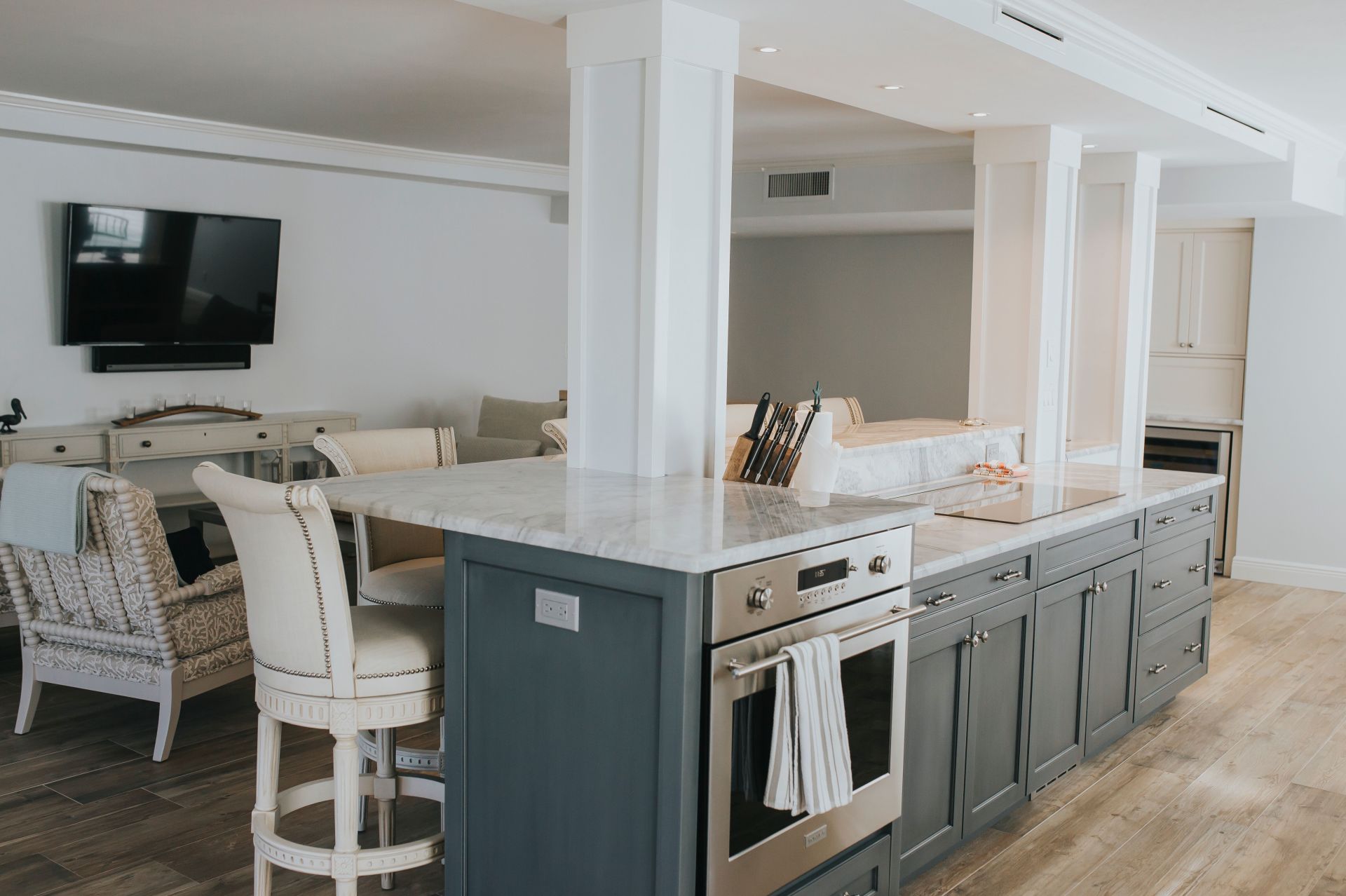 A kitchen with a large island, stainless steel appliances, and a flat screen tv.