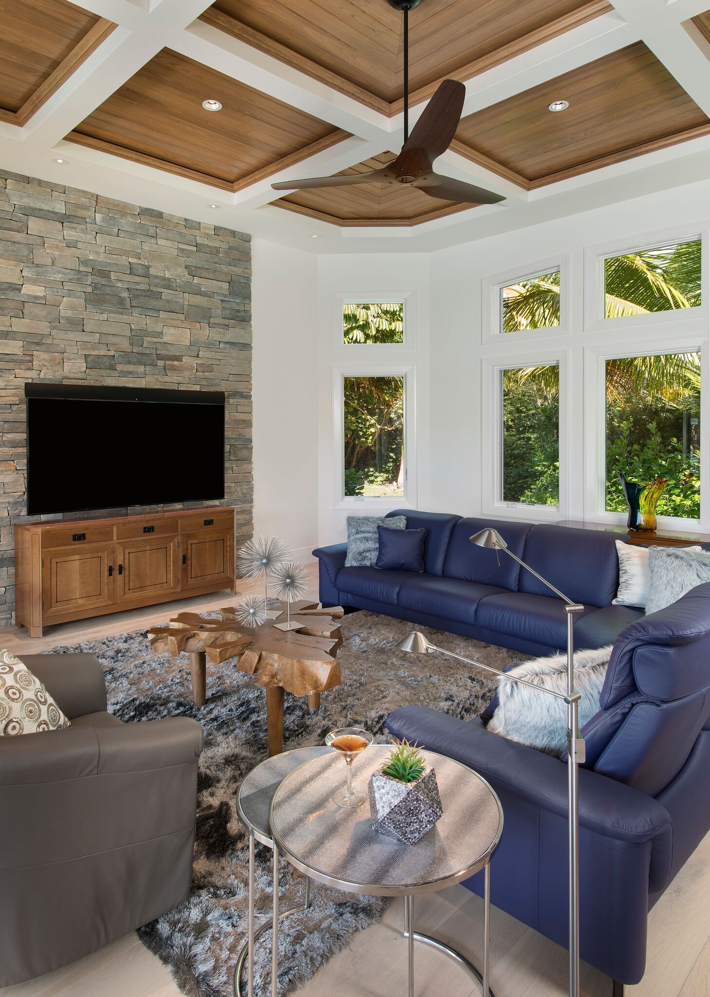 A living room with a couch, chairs, a television and a ceiling fan.