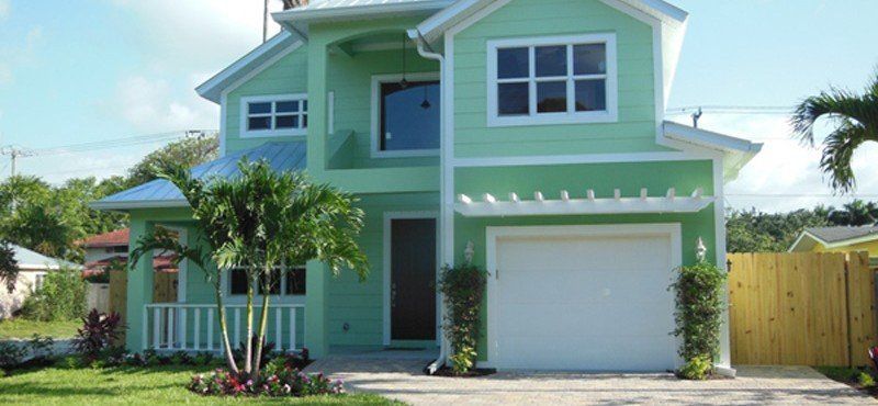 A green house with white trim and a white garage door.