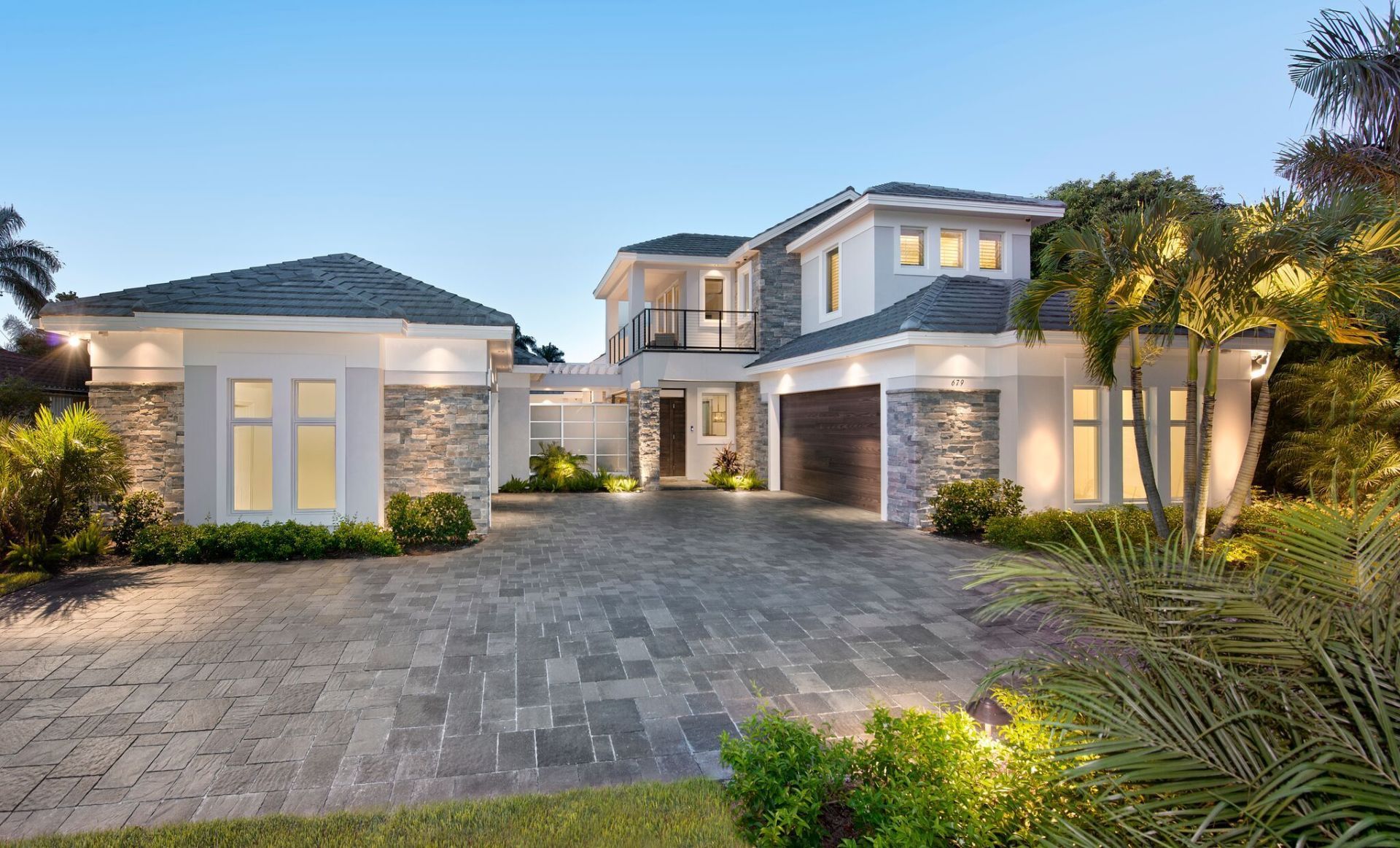 A large white house with a brick driveway in front of it.