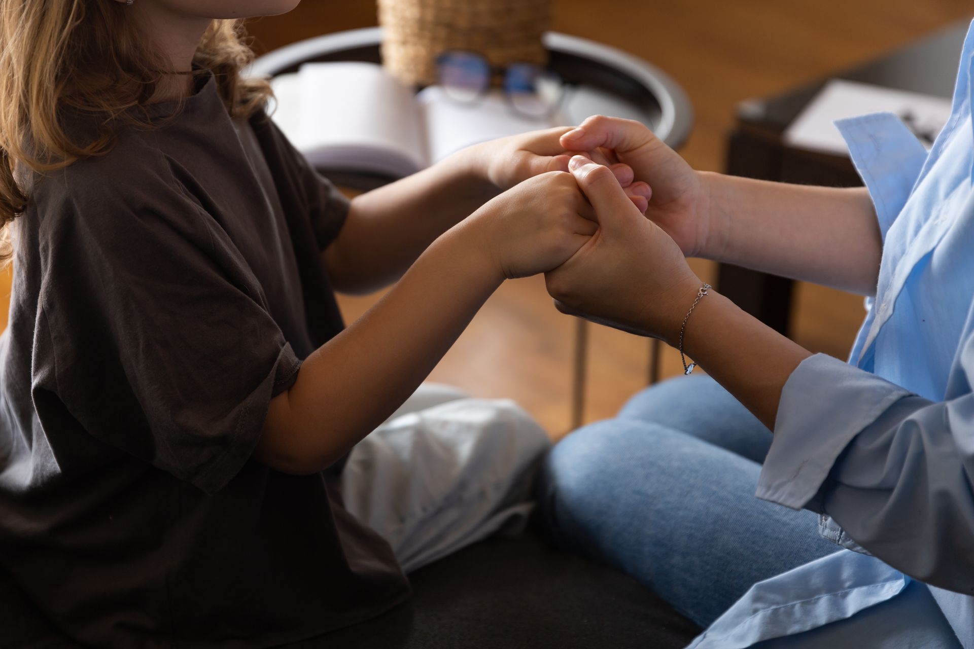 Woman in straw hat smiles, holding wine glass near a lake.