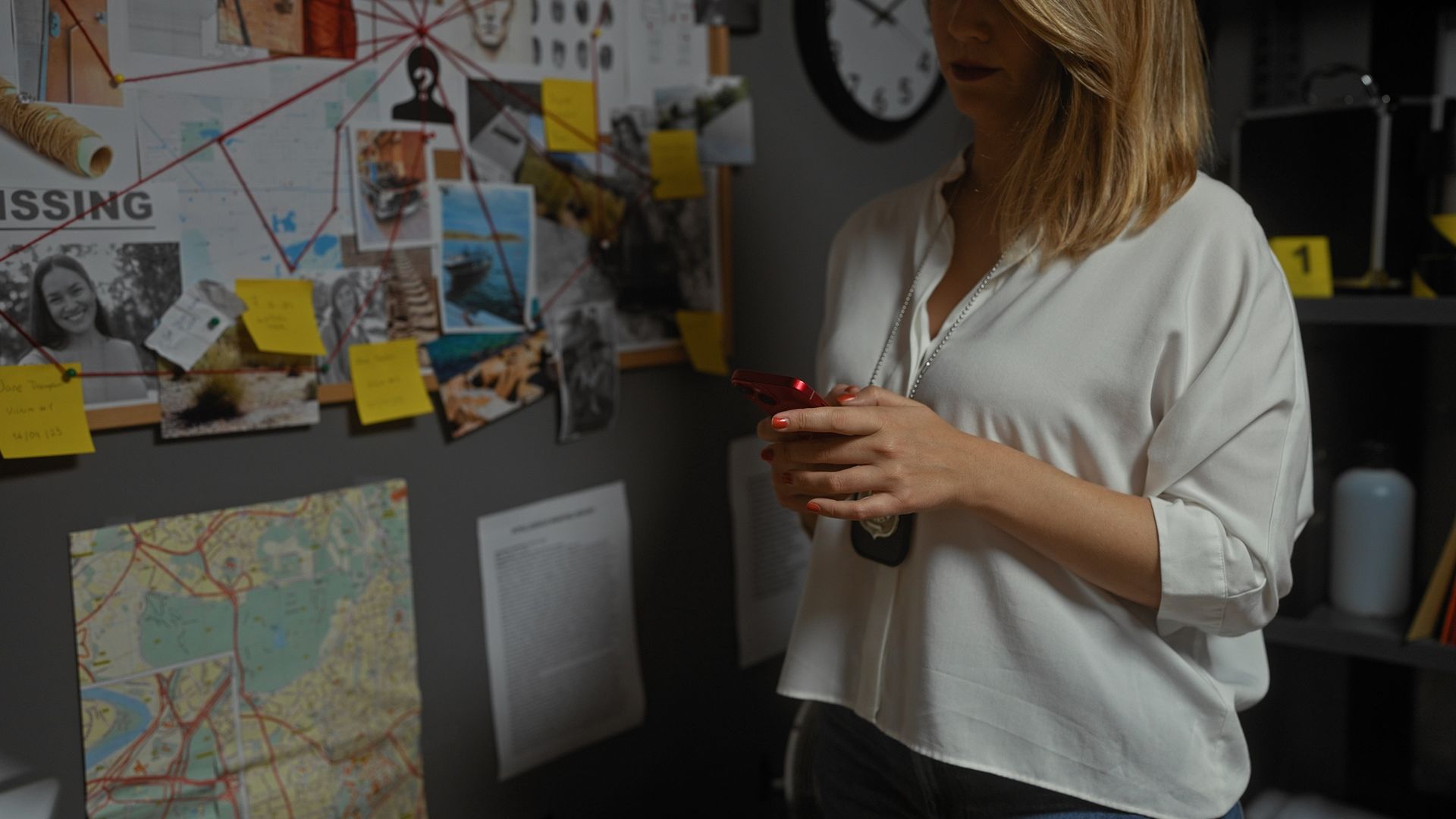 Woman in straw hat smiles, holding wine glass near a lake.