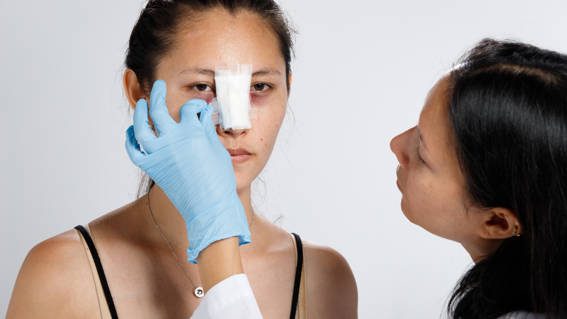 Woman getting bandages taken off after rhinoplasty