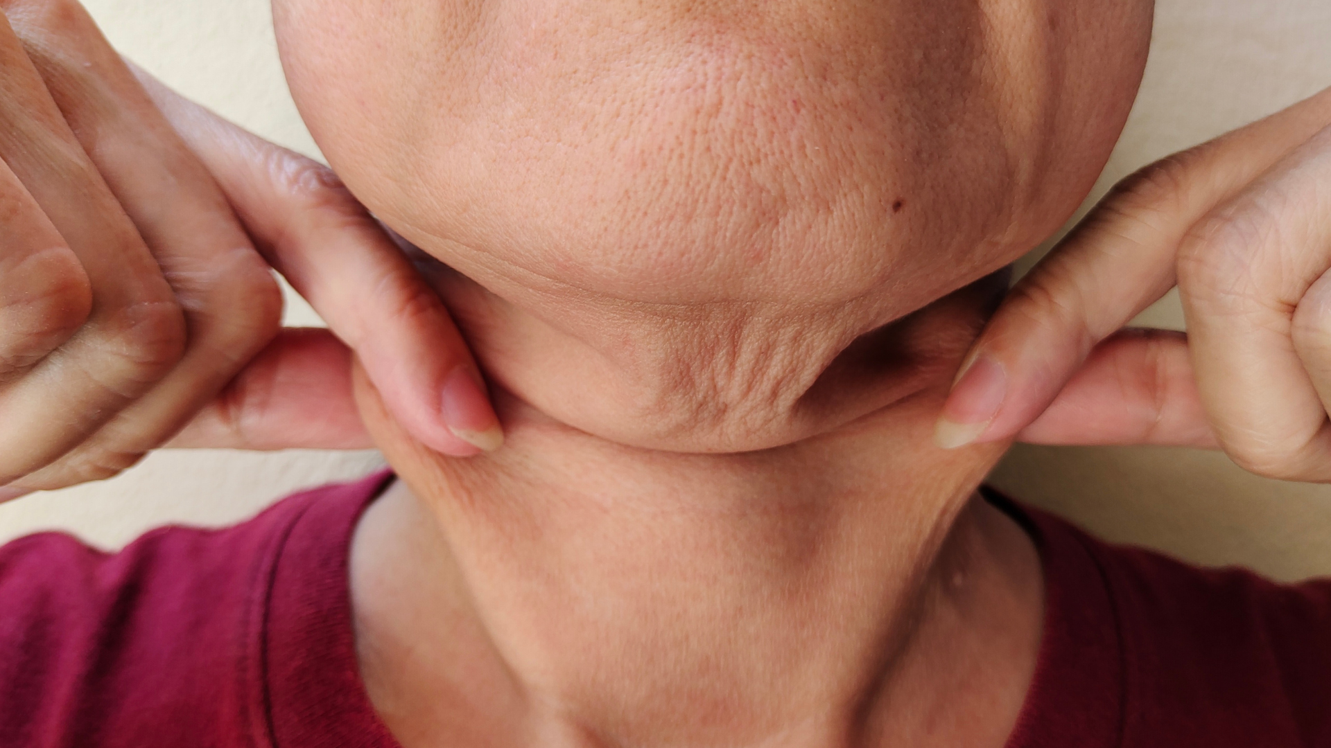 close up of womans neck, lifting sagging skin with fingers