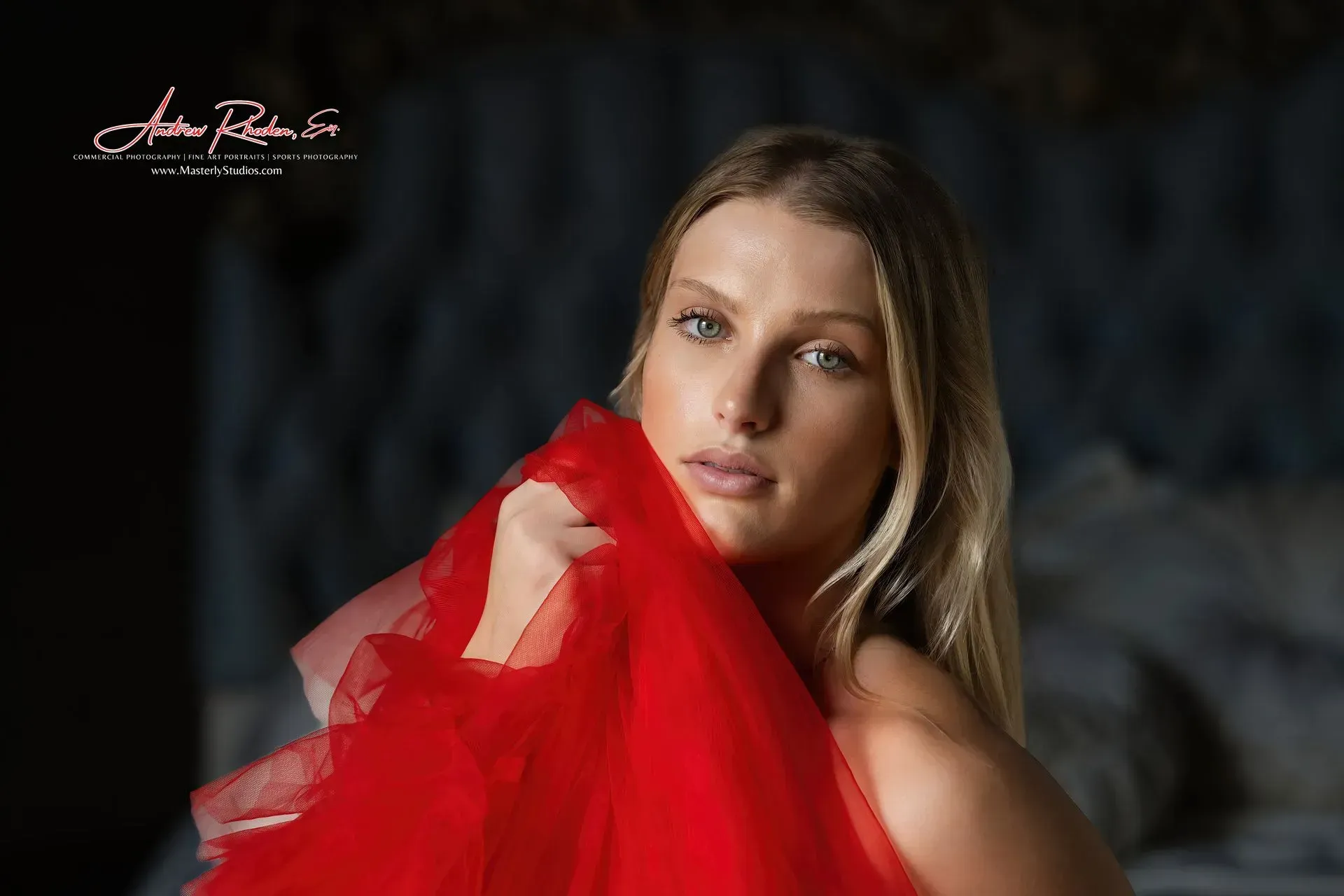 Woman with blonde hair, red fabric. Soft lighting, bedroom setting.