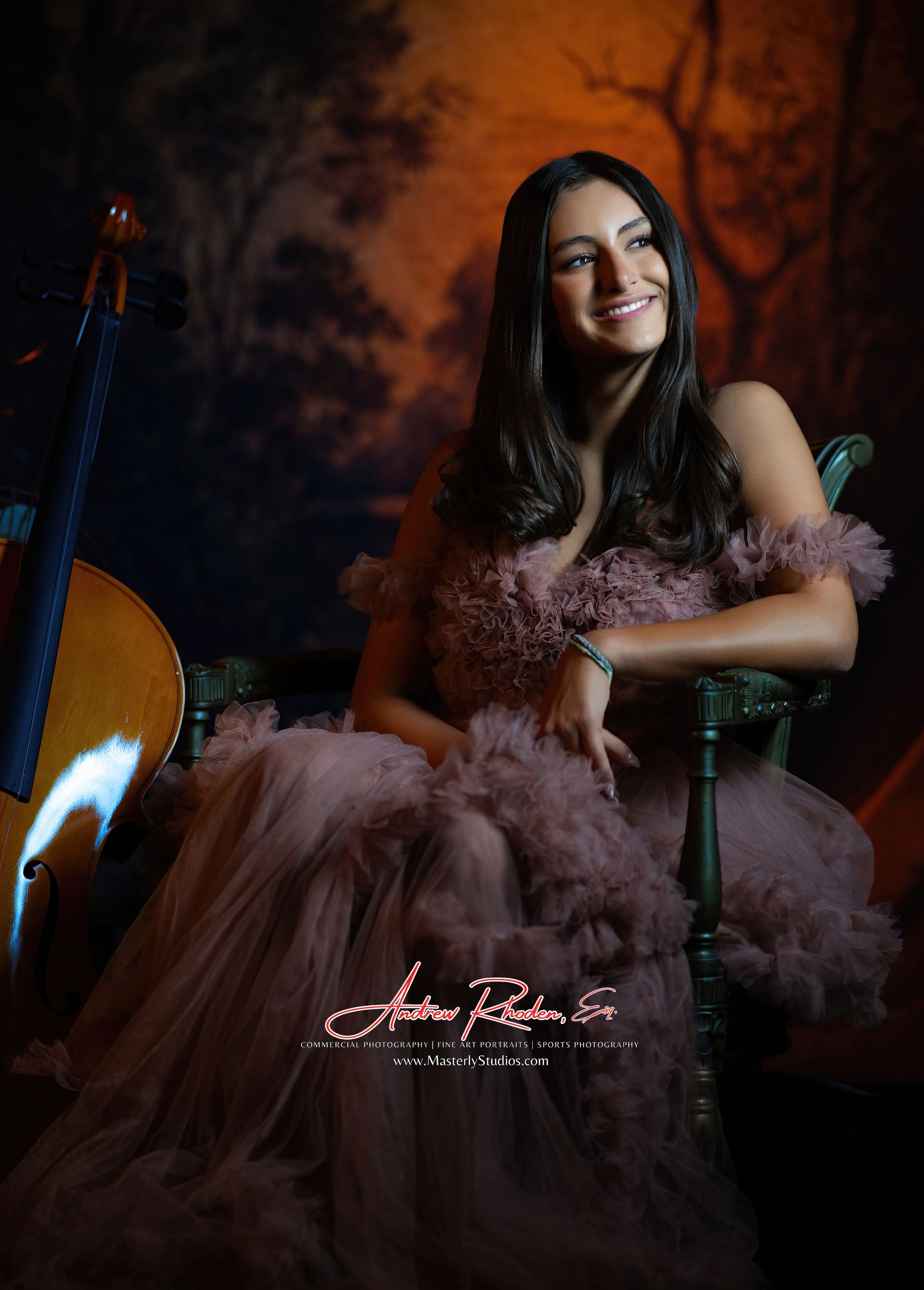 Woman in a mauve gown smiles, seated next to a cello. Warm-toned studio backdrop.