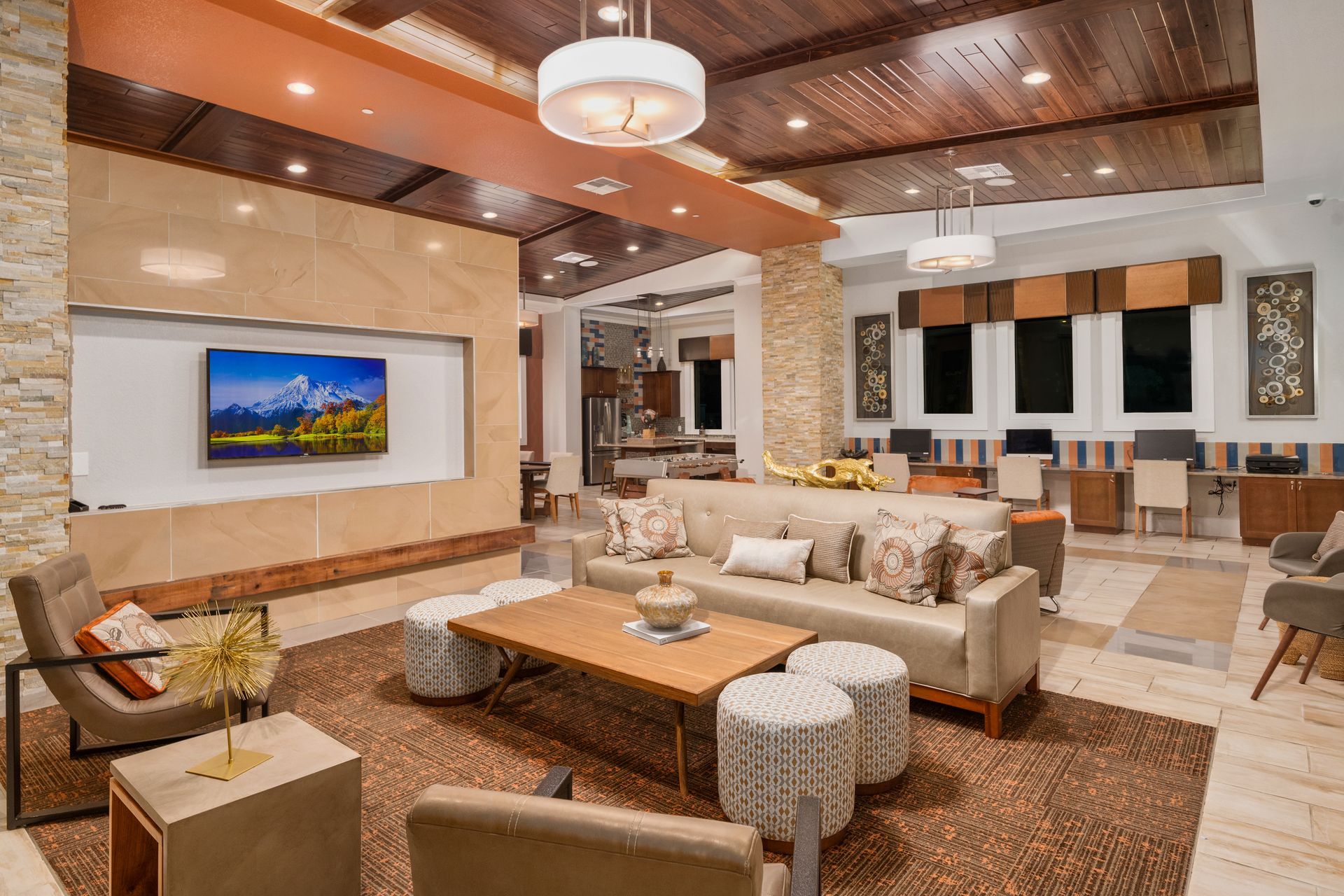Cozy living room with couch, ottomans, TV, wooden ceiling, and beige walls.