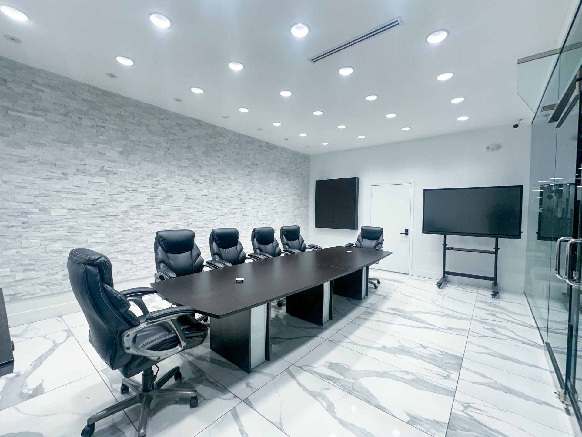 Bright, open room with tables, chairs, and large windows; reflective floor.