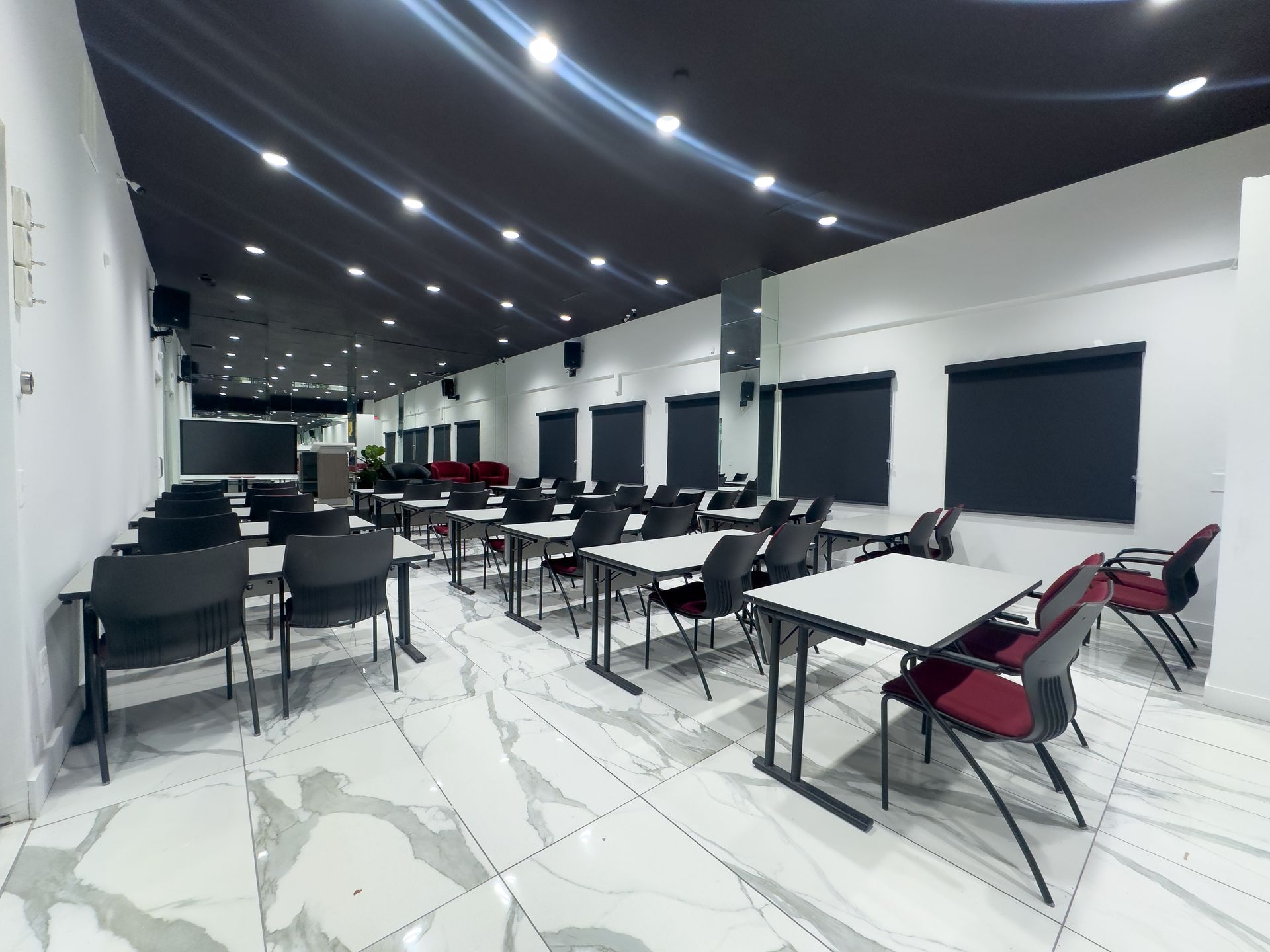 Classroom with rows of desks and burgundy chairs, white walls, and marble floors.