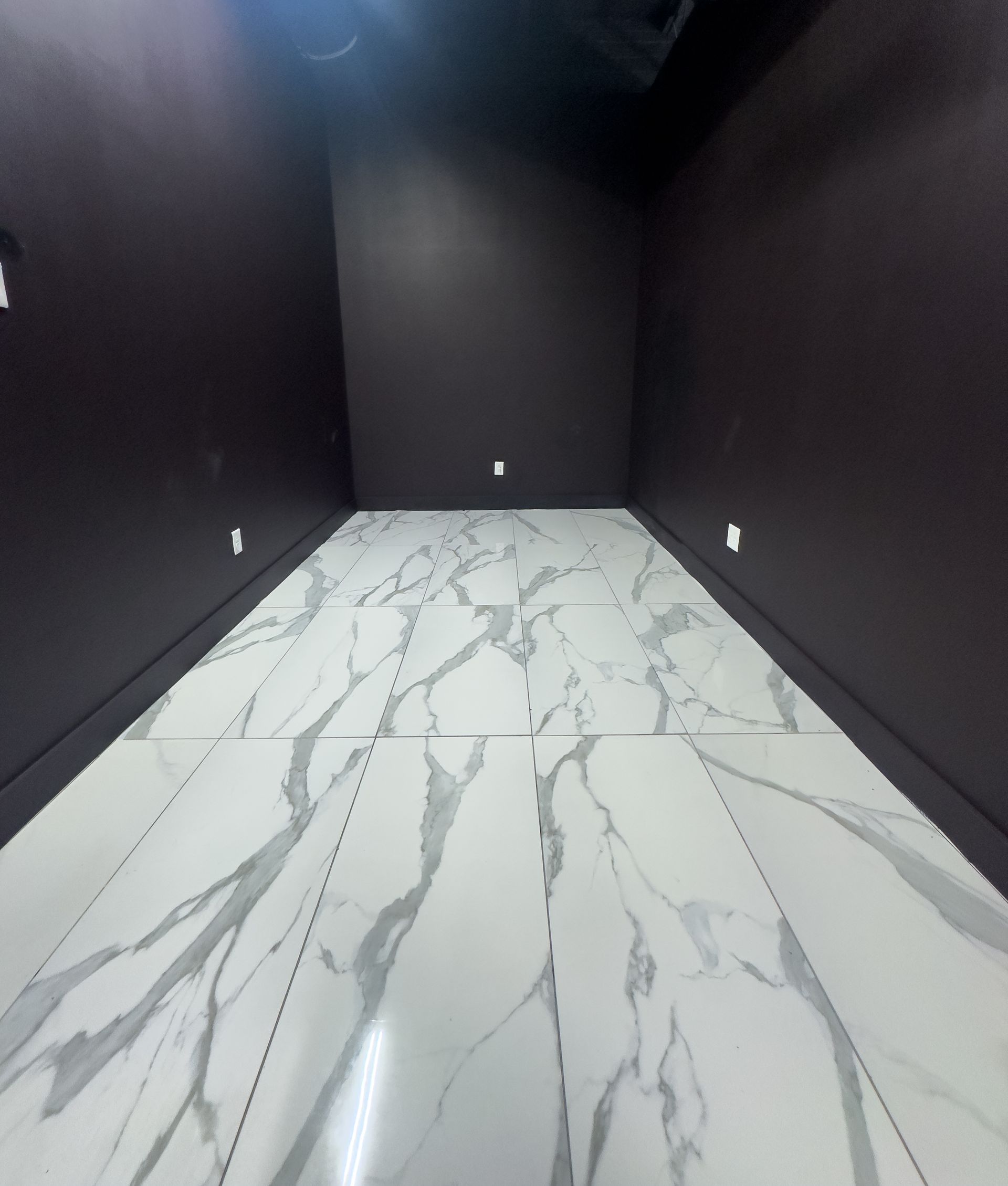 A photography studio setup with a laptop, lighting equipment, and a stool against a white backdrop.