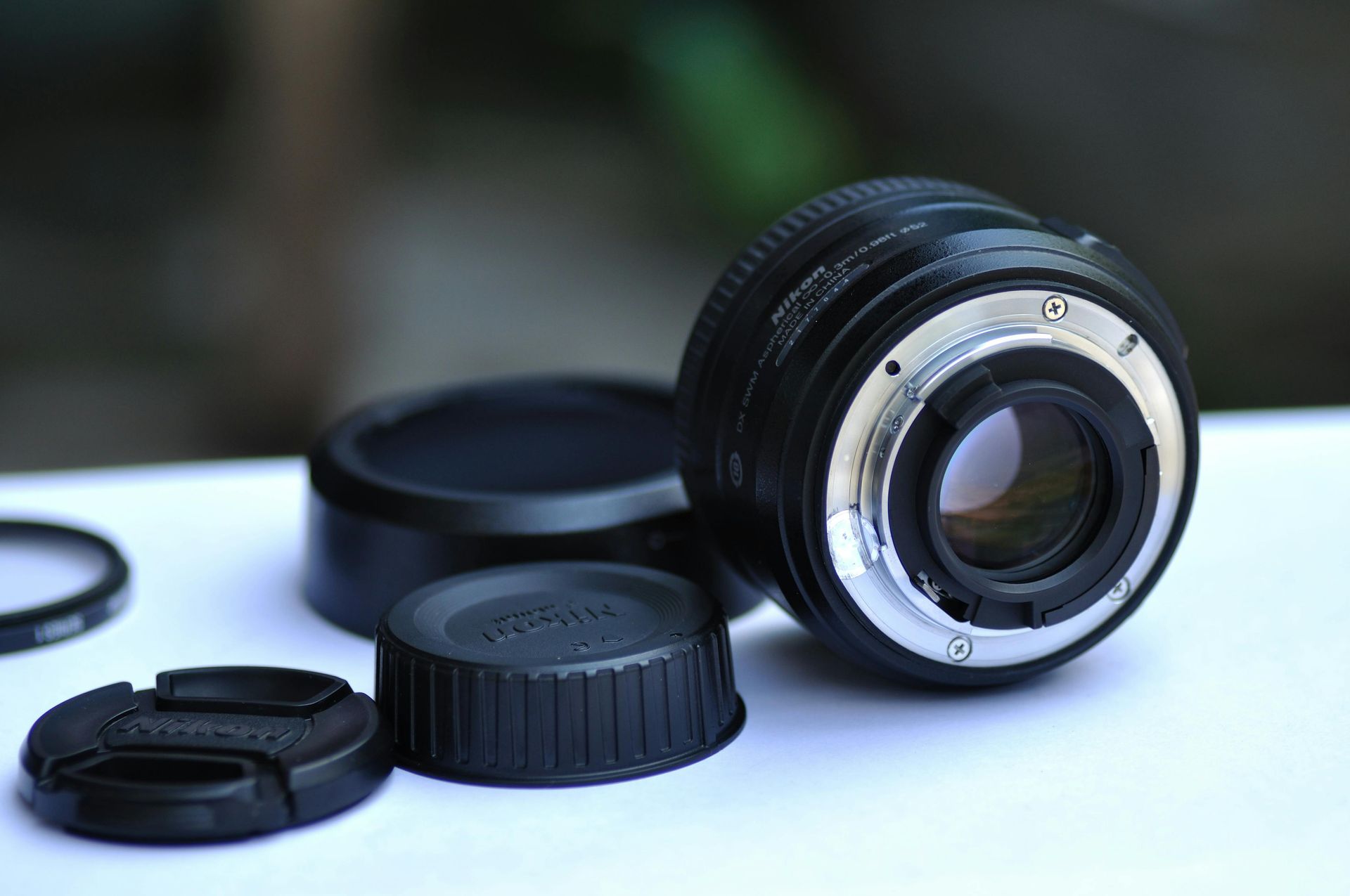 Camera lens with lens cap and other accessories on a white surface.
