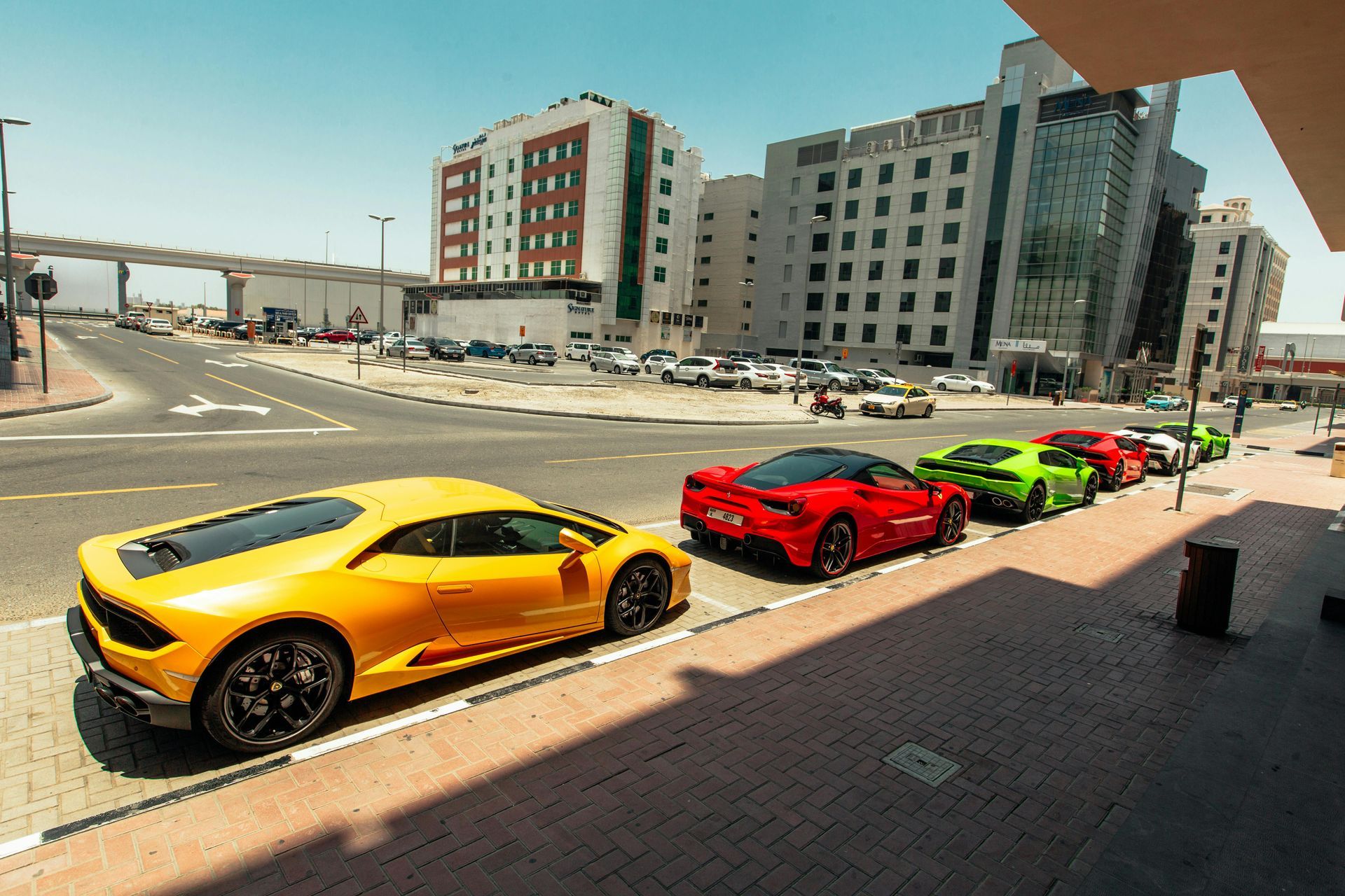 Yellow Lamborghini parked with other sports cars on a city street.