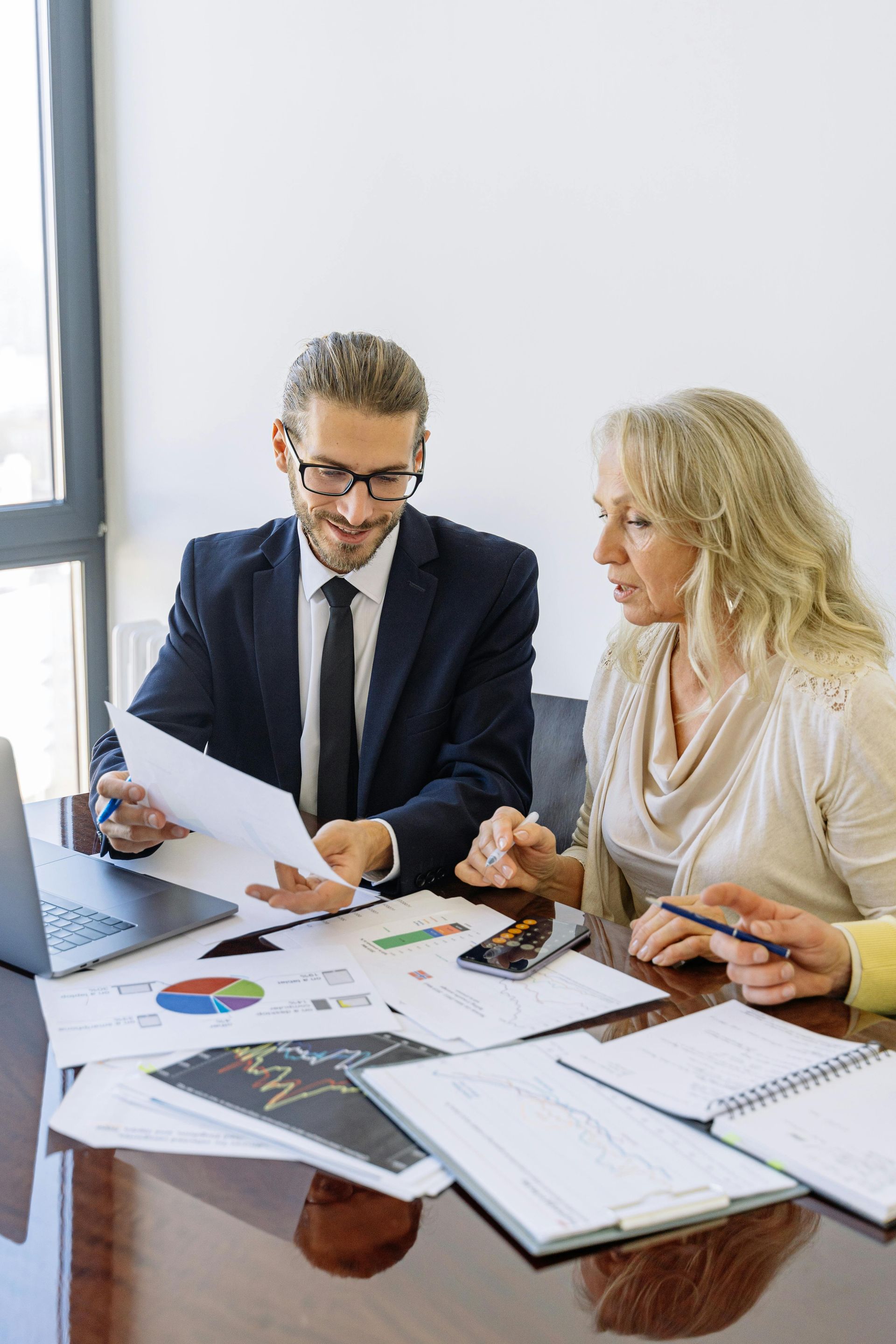 Two coworkers reviewing charts and notes at a desk during a business meeting