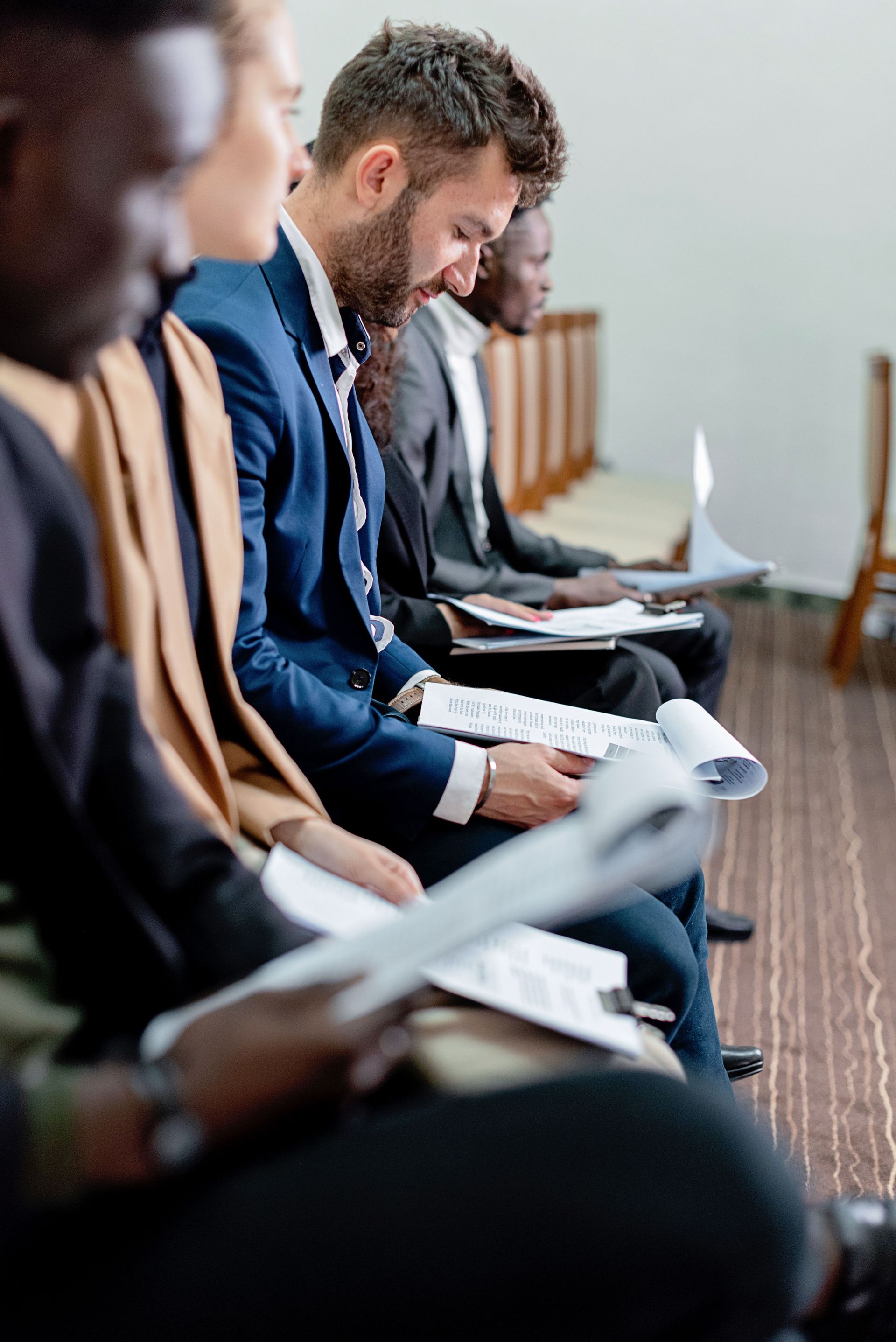 People seated in a row reading papers during a meeting or conference.