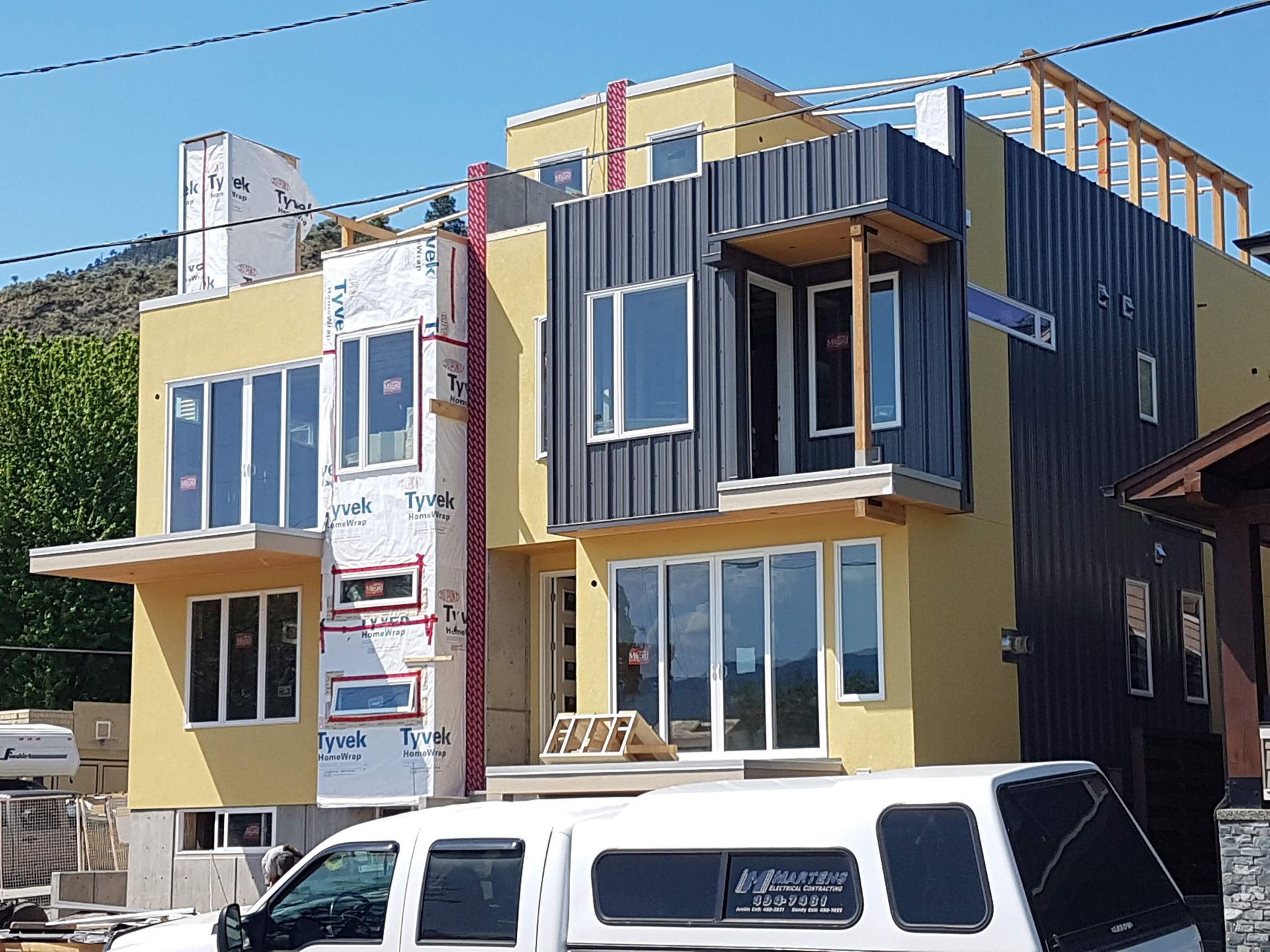 A white van is parked in front of a building under construction.