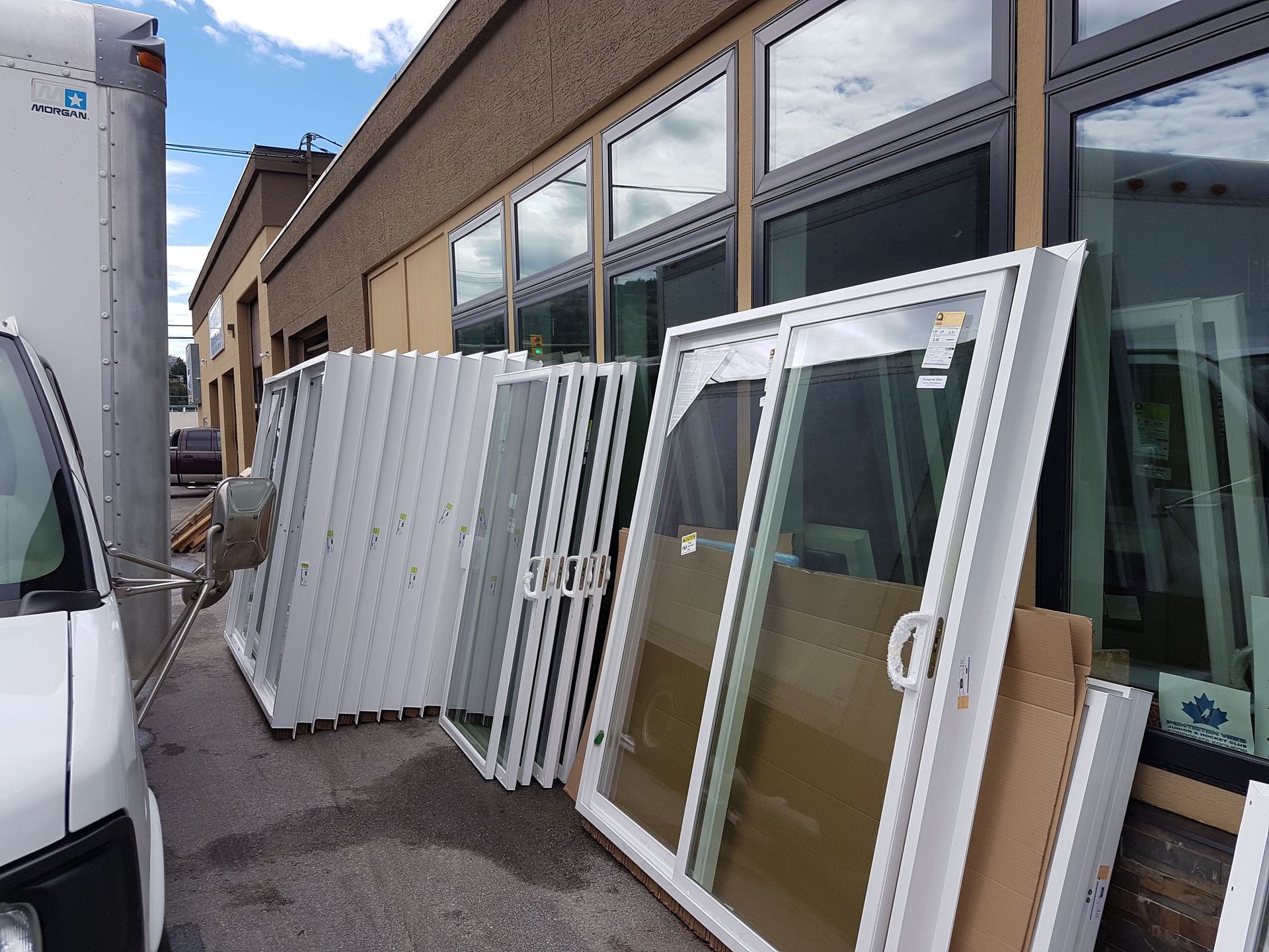 A white van is parked in front of a building with lots of windows stacked on top of each other.