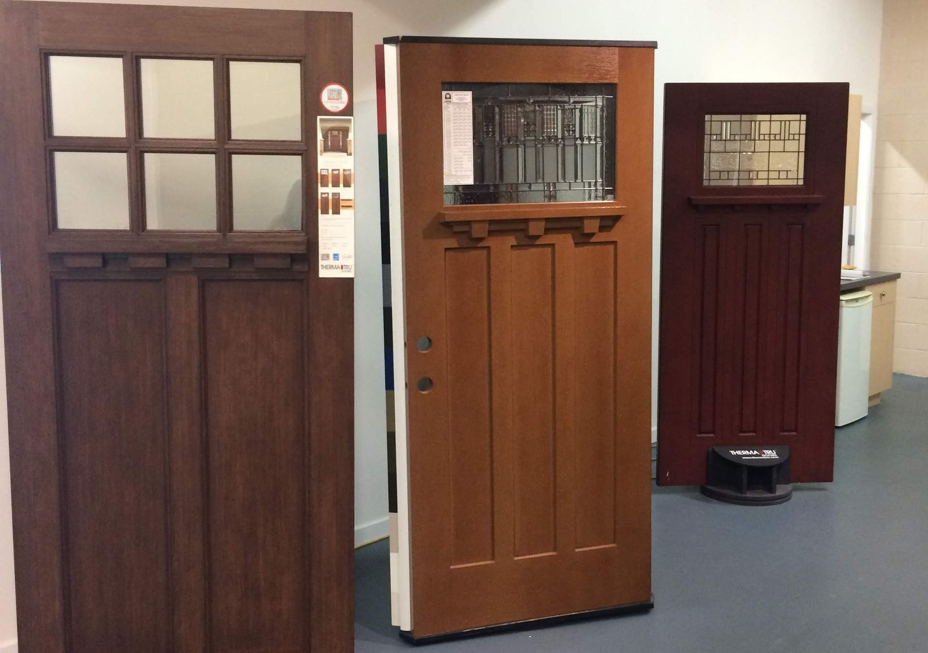 Three wooden doors of varying designs displayed indoors.