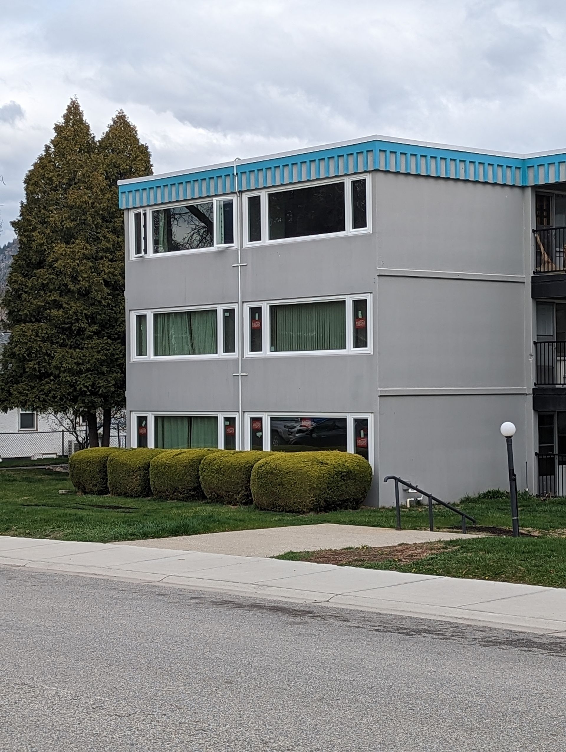 A large apartment building with a blue roof is sitting on the side of the road.