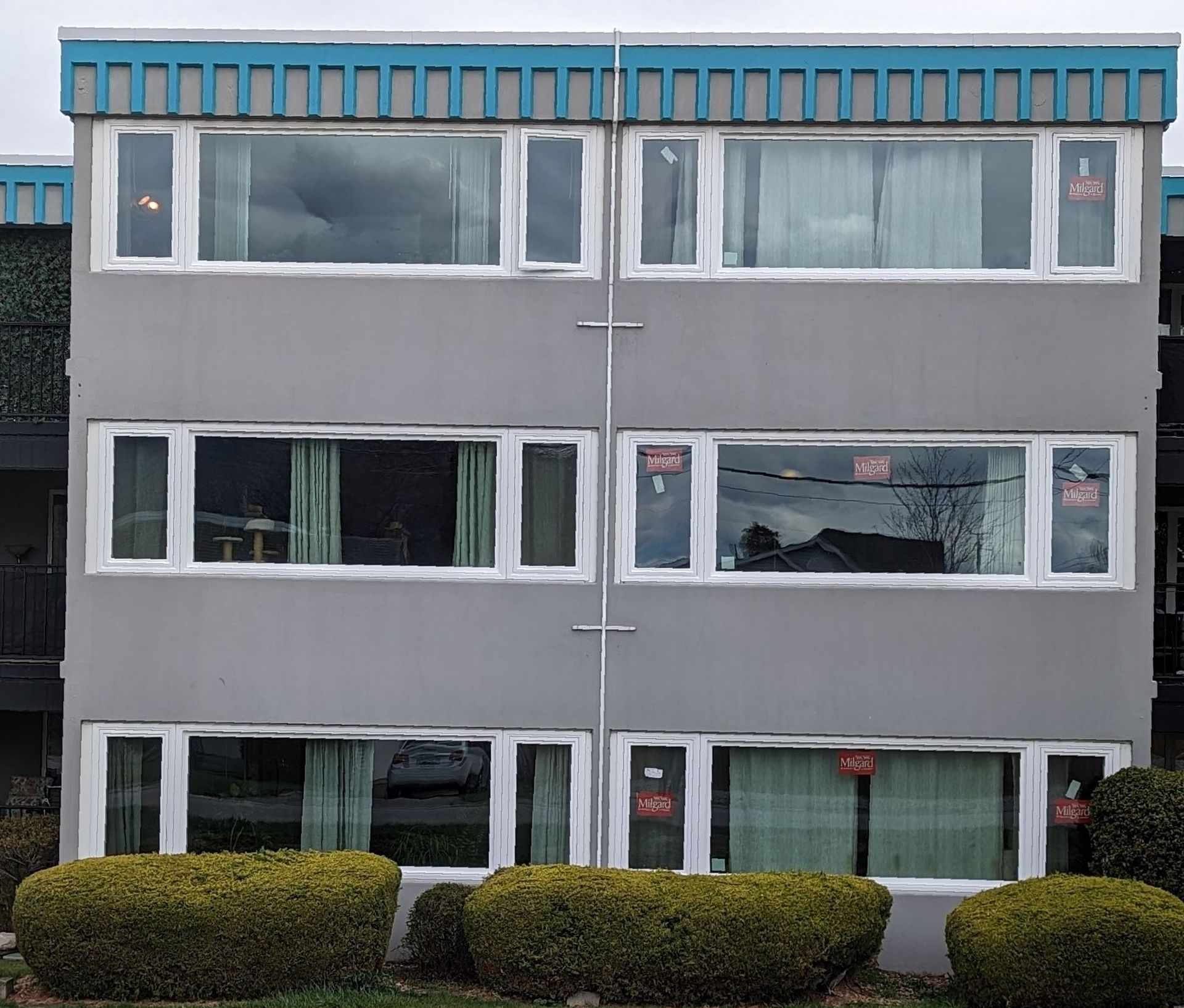 A building with a lot of windows and bushes in front of it