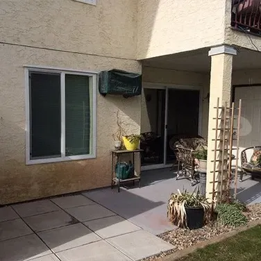 A patio with a sliding glass door and a window on the side of a house.