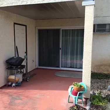 A patio with a sliding glass door and a grill.