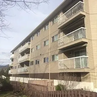 A large apartment building with balconies and a fence in front of it.