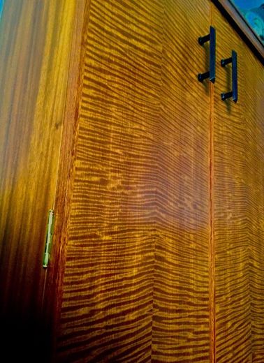 A close up of a wooden cabinet with black handles.