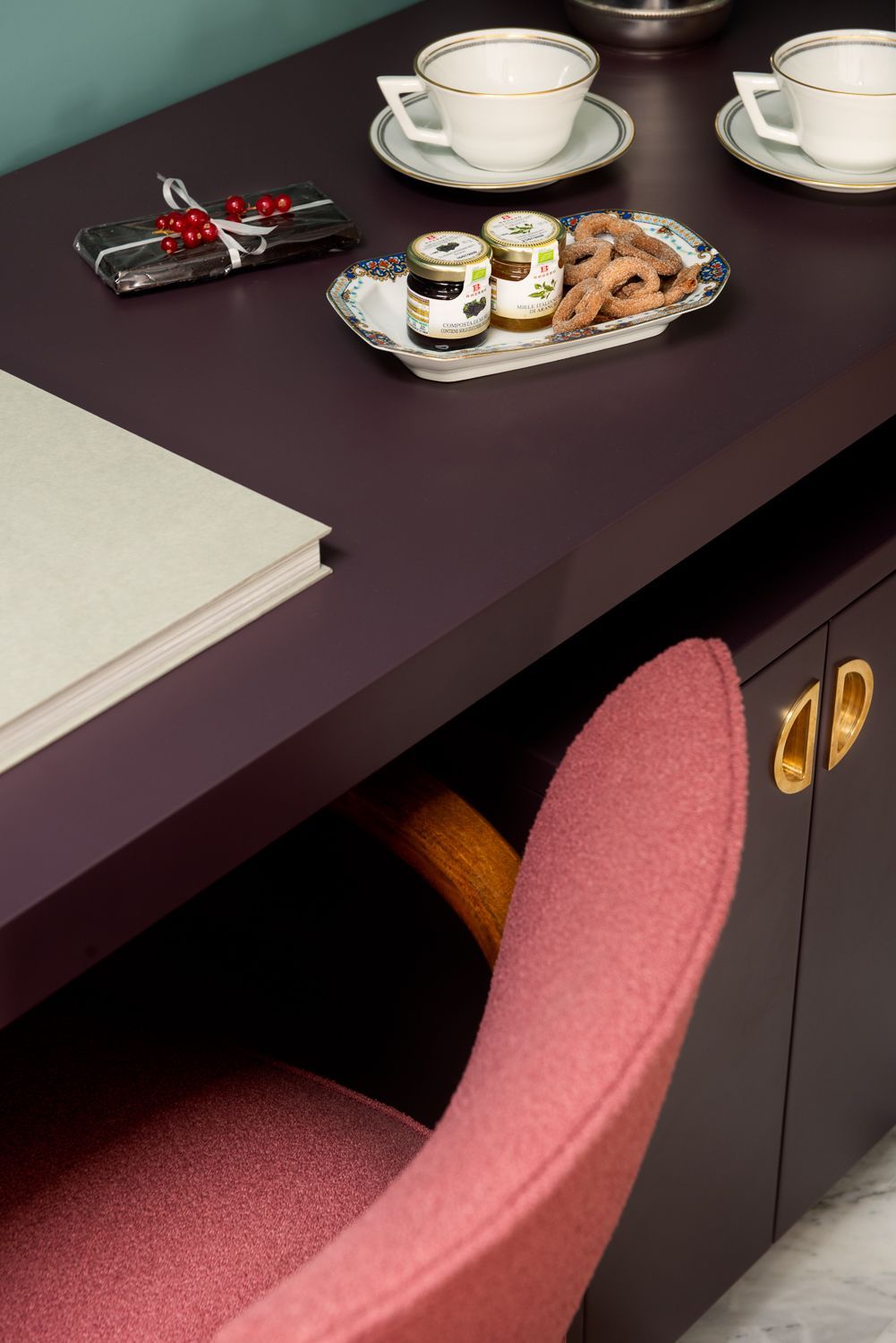 Dark purple desk with pink chair, tea cups, snacks, and a notepad.
