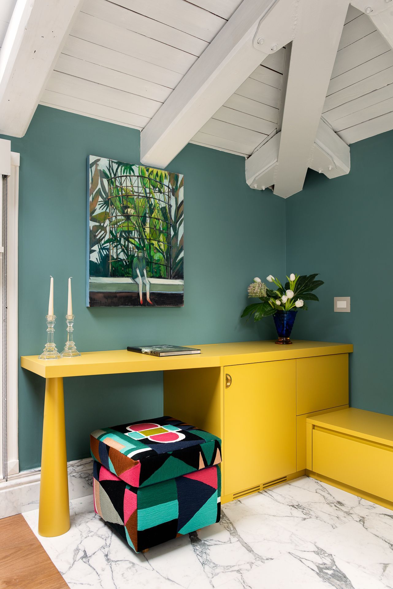 Sala de estar con dos sillones estampados, tragaluz y pared verde azulado.