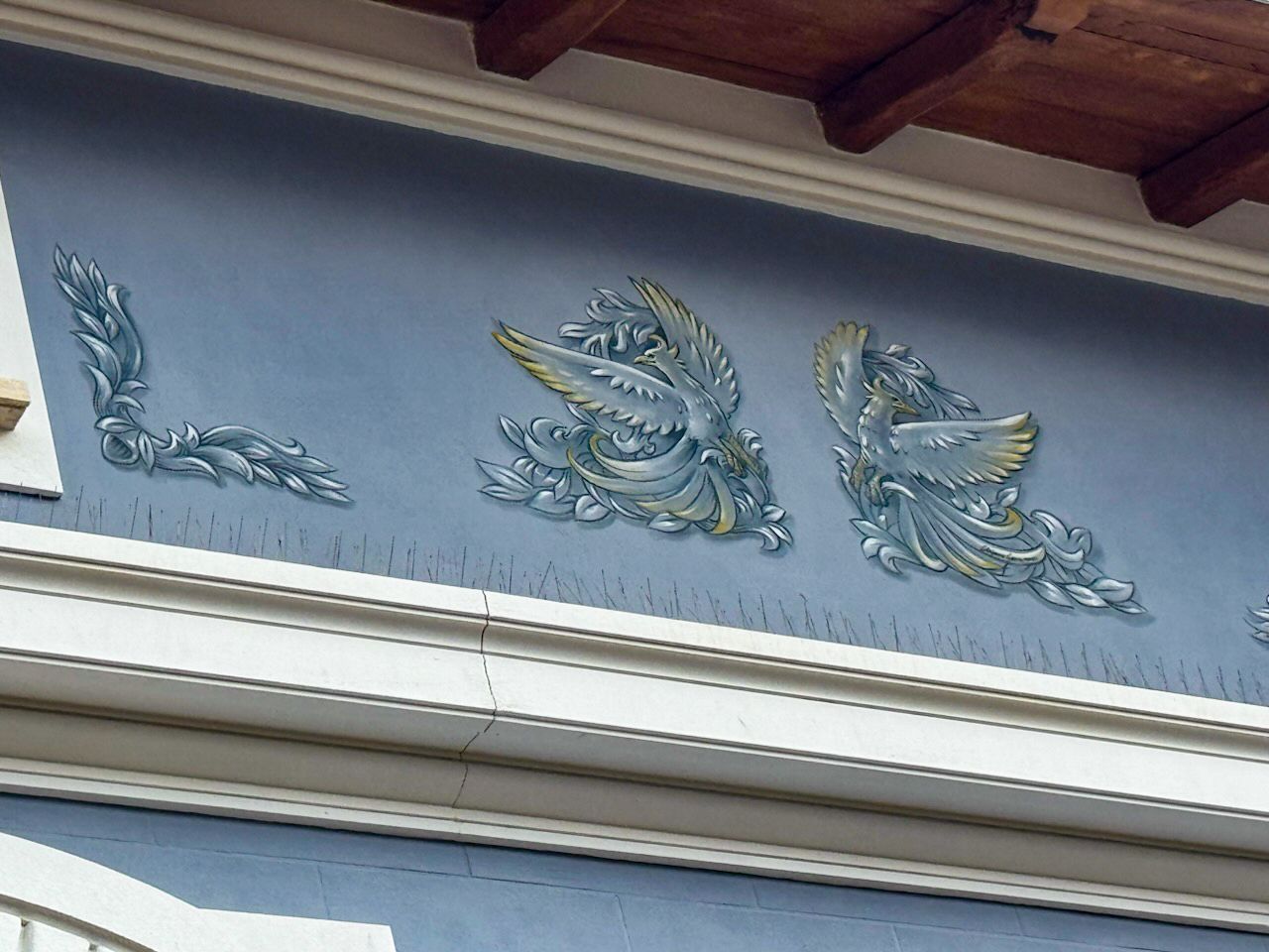Facciata blu dell'edificio con ornamenti decorativi in ​​rilievo; uccelli stilizzati e fogliame.