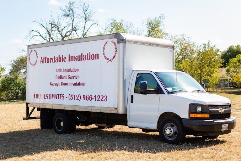 A white affordable insulation truck is parked in a field