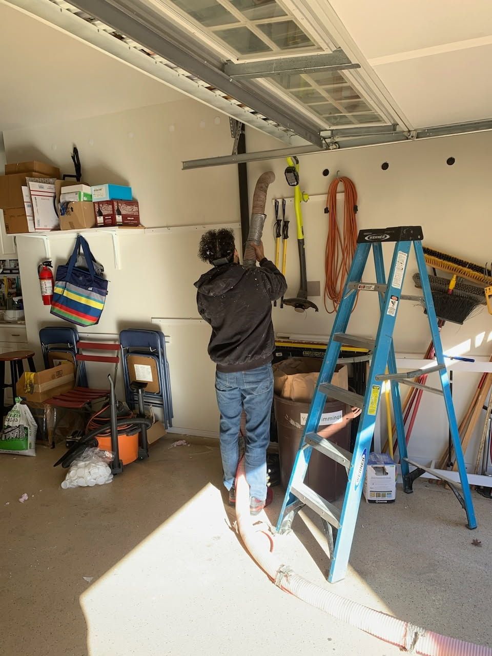 A man standing in a garage next to a blue ladder