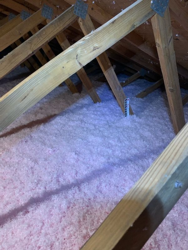 An attic with pink insulation and wooden beams