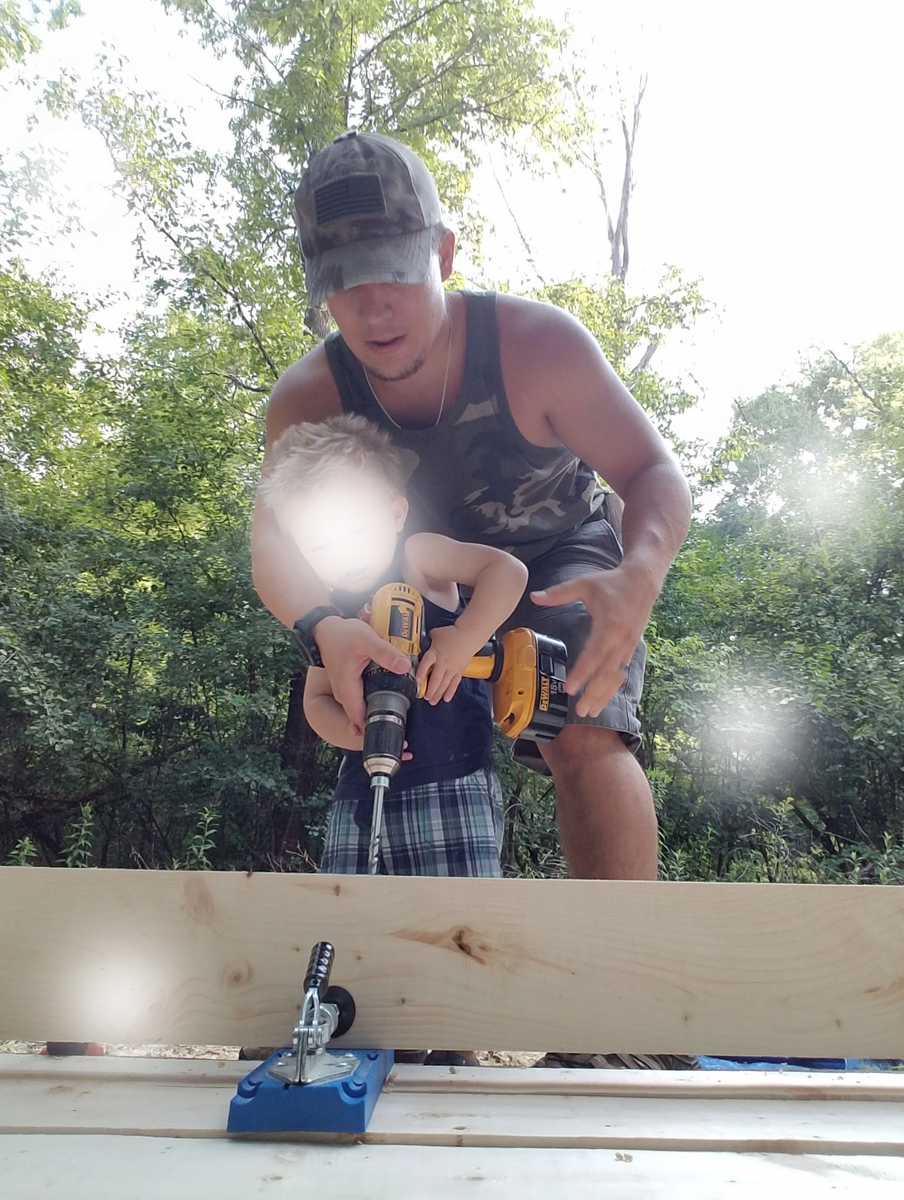 Man and young child drilling wood outdoors