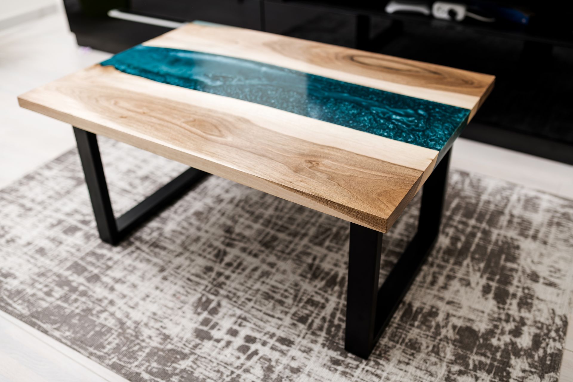 Coffee table with wooden top and turquoise resin river on a rug