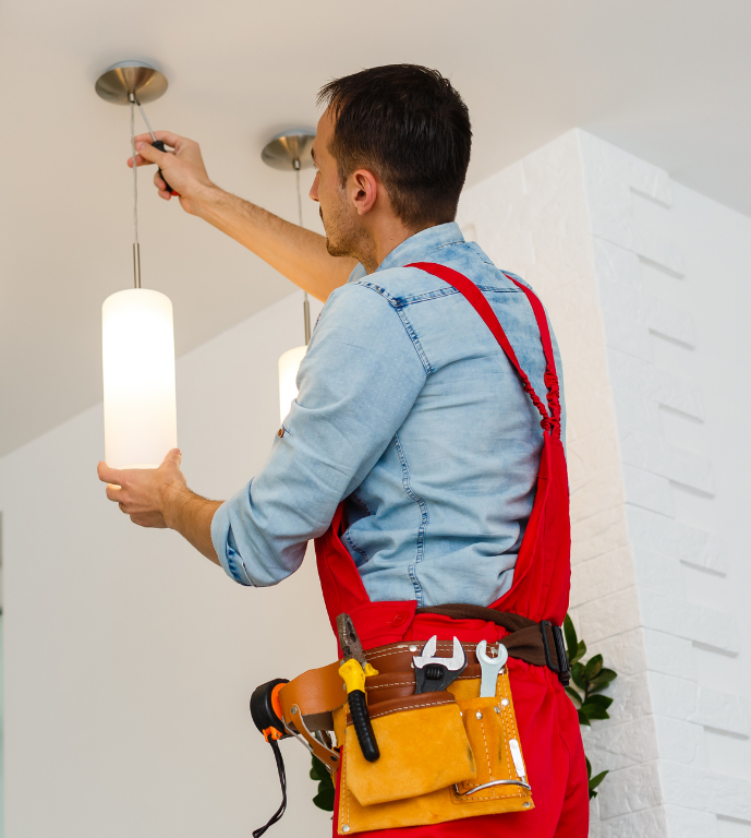 An electrician in safety gear is inspecting an open electrical distribution panel with neatly arranged wiring.