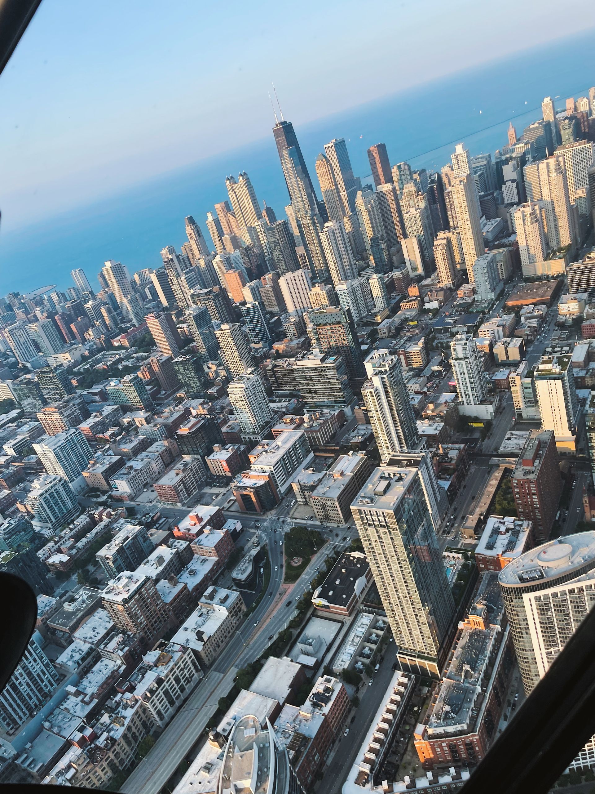 Aerial view of a city with skyscrapers and a body of water, under a blue sky.