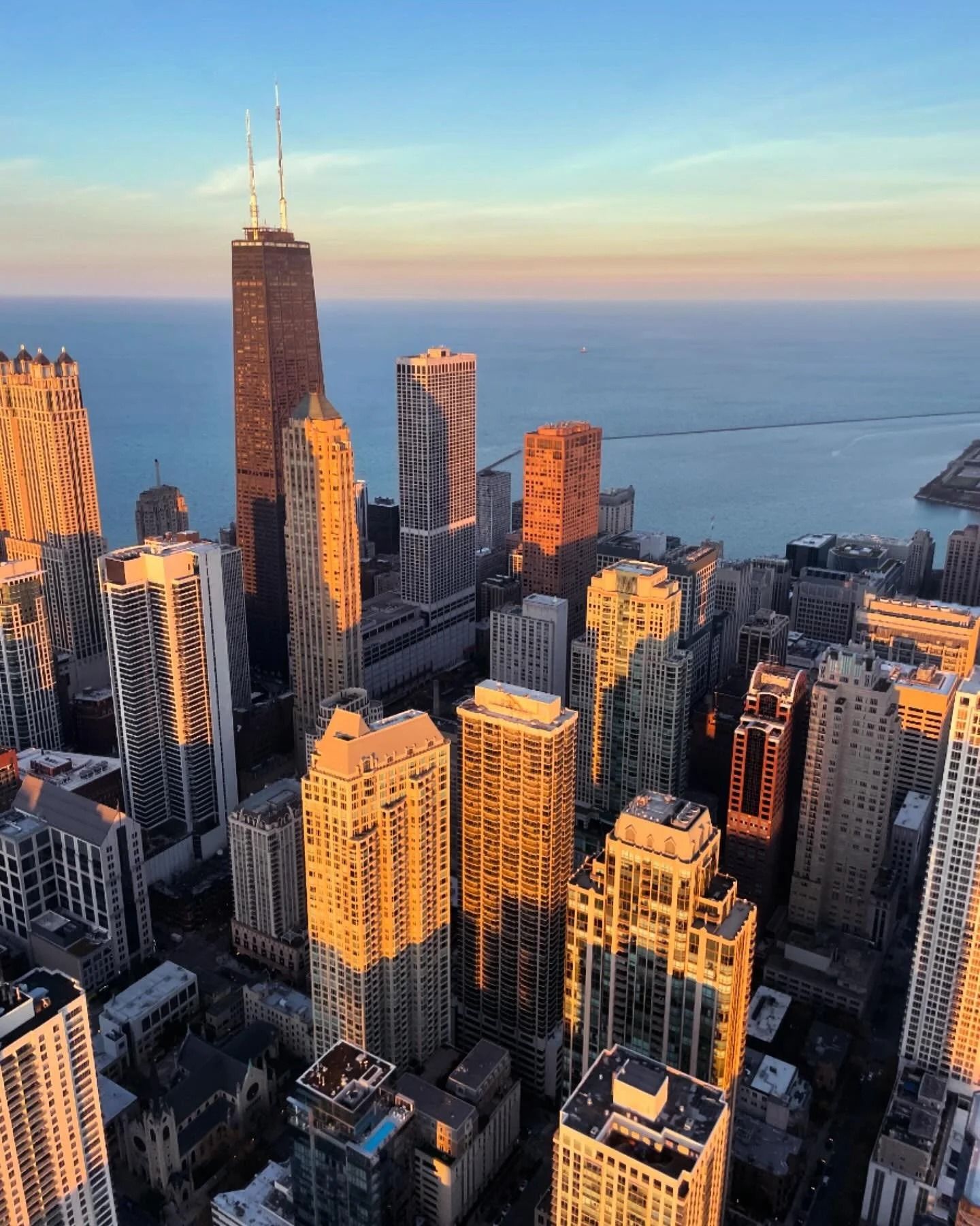 Chicago skyline at sunset with buildings casting long shadows; Lake Michigan in background.