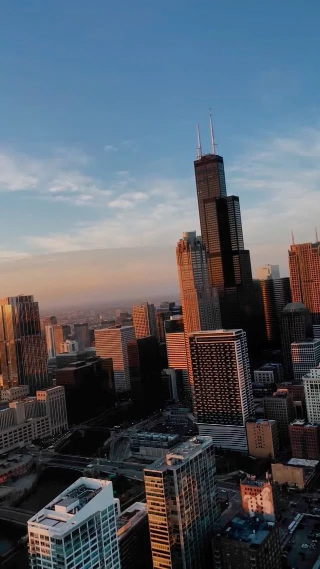 Chicago skyline with Willis Tower at sunset, buildings, and blue sky.
