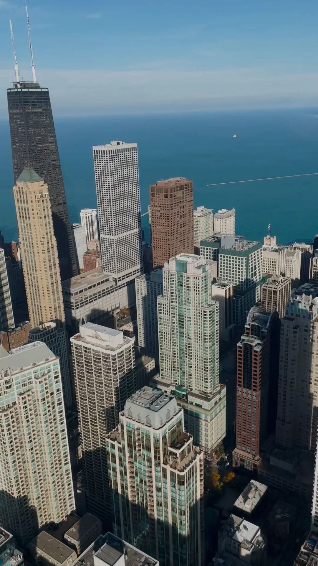 Aerial view of Chicago skyscrapers along Lake Michigan on a sunny day.