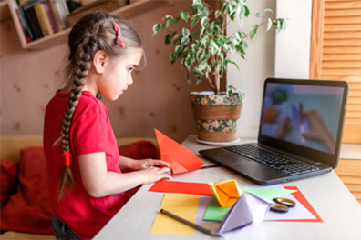 a little girl is sitting at a desk in front of a laptop computer