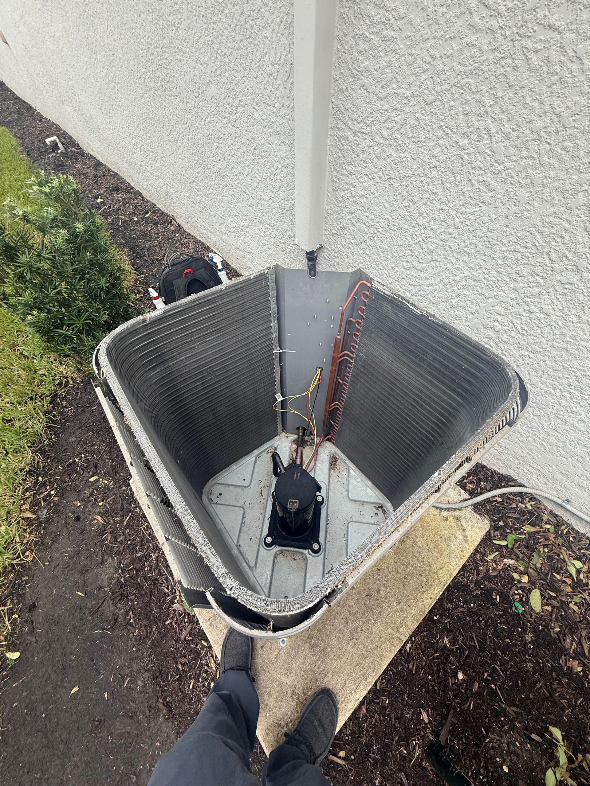 Open utility drain with black cable or device inside beside sidewalk and grass.