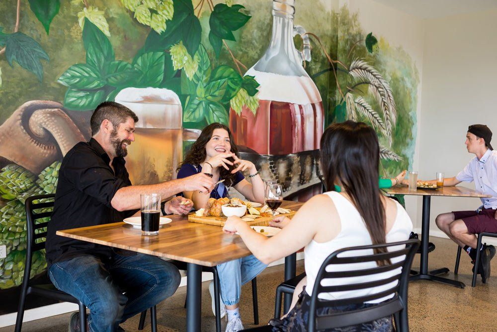 A Group of People Are Sitting at Tables in a Restaurant Eating Food — Monty Brewing Co. In Highfields, QLD