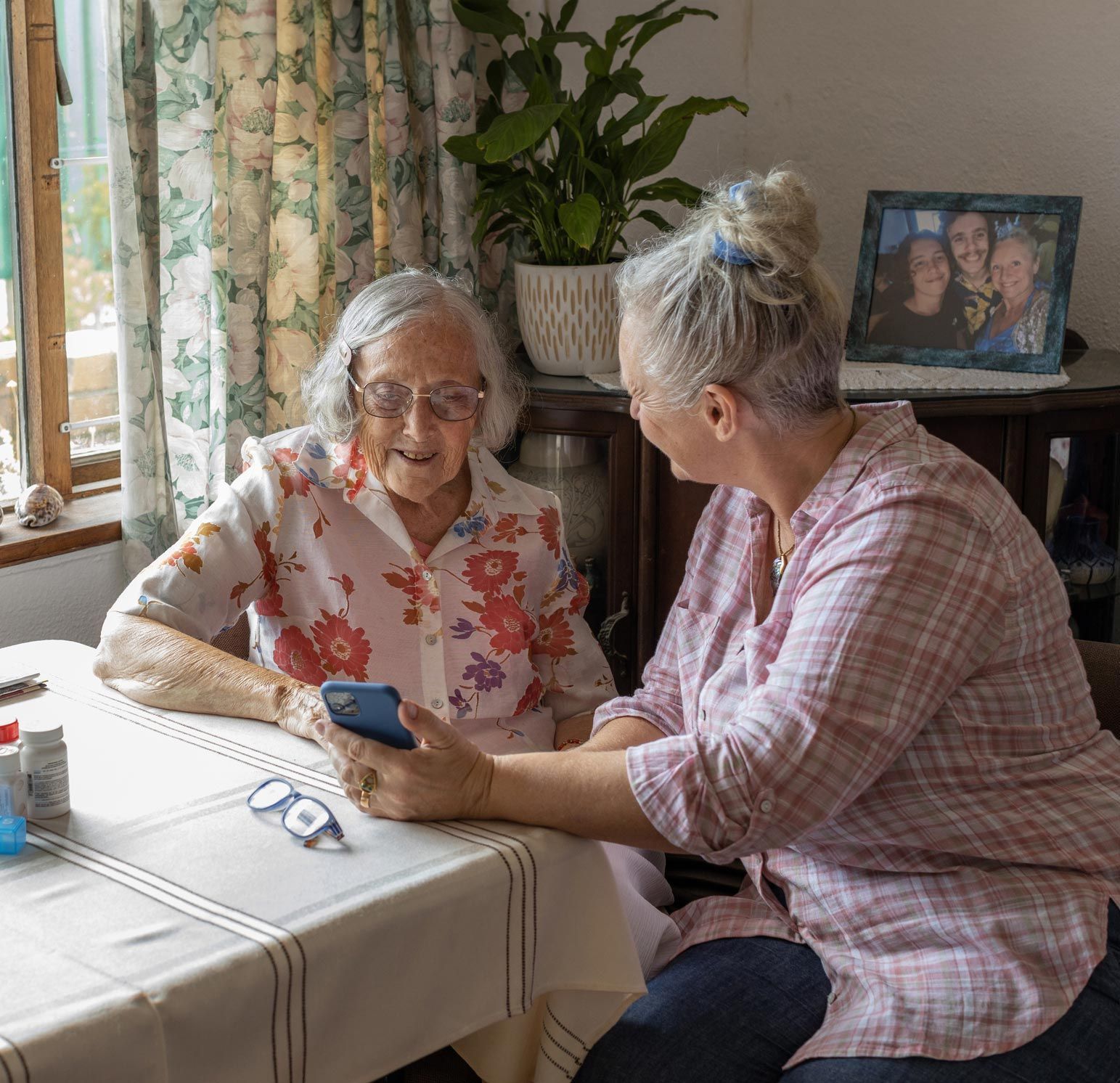 Two Elderly Women Looking At Phone — Princeton, IN — Friends and Family Caregivers