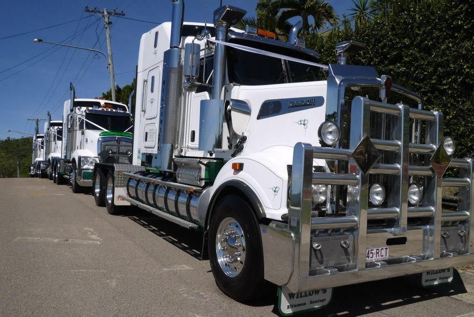 A Row Of Semi Trucks Are Parked On The Side Of The Road — Willow's Bitumen Haulage Pty Ltd In Queensland
