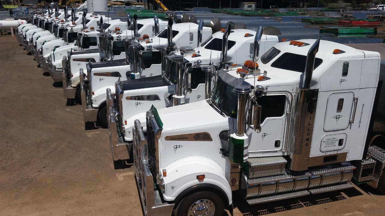 A Row Of Semi Trucks Are Parked In A Parking Lot — Willow's Bitumen Haulage Pty Ltd In Stuart, QLD