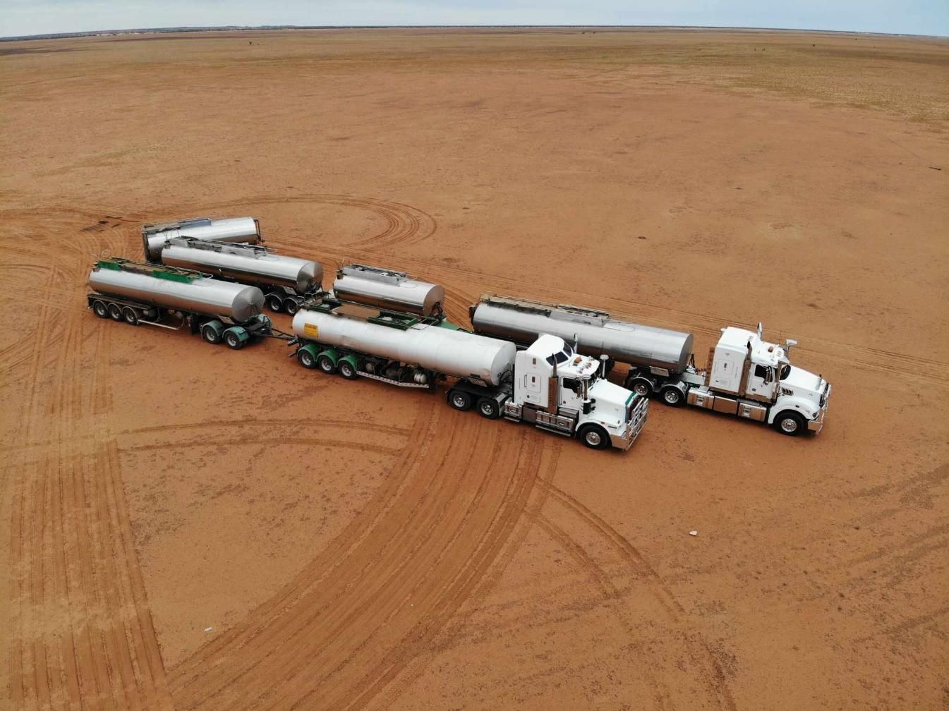 A Row Of Tanker Trucks Are Parked In A Dirt Field — Willow's Bitumen Haulage Pty Ltd In South Australia