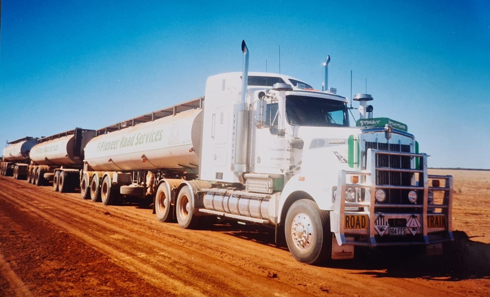 A White Semi Truck Is Driving Down A Dirt Road — Willow's Bitumen Haulage Pty Ltd In New South Wales