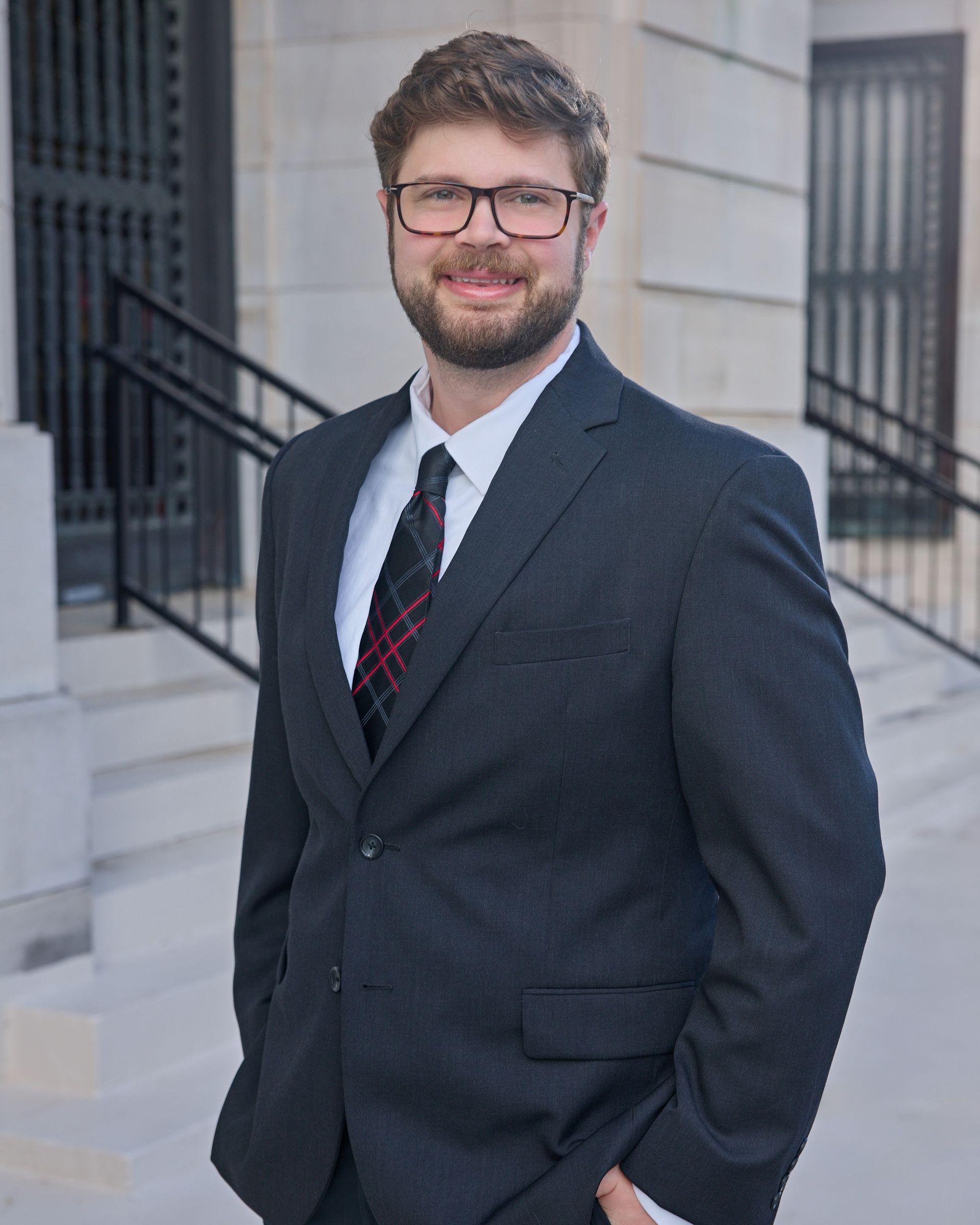 A bald man with a beard is wearing a suit and tie.